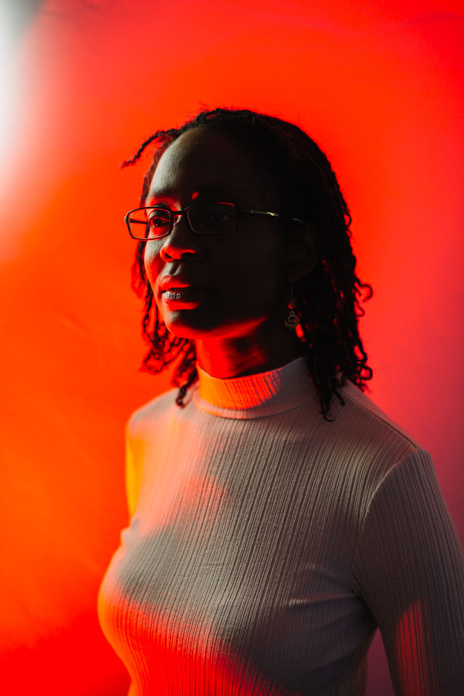 Autorin Sharon Dodua Otoo vor einem roten Hintergrund. 