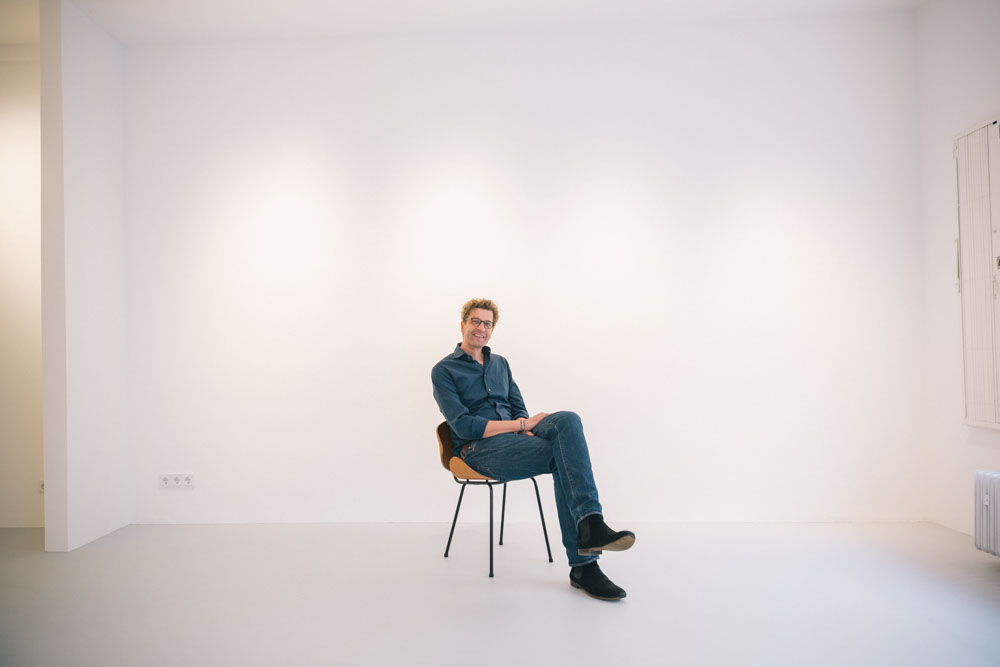 Peter Sillem sitzt auf einem Stuhl in seiner neuen Galerie. 