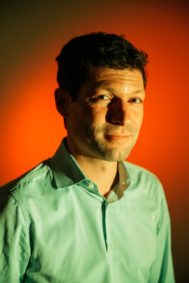 Ronen Steinke posiert vor einem farbigen Hintergrund. 