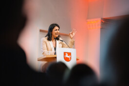 Preisträgerin Düzen Tekkal spricht auf der Bühne am Mikrofon und gestikuliert.