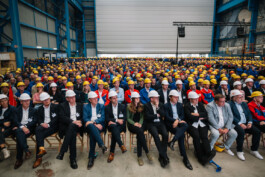 Politiker*innen und Mitarbeitende sitzen in einer großen Werkshalle der Meyer Werft. 