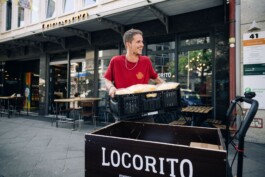 Ein Mitarbeiter trägt eine Kiste mit Lebensmitteln zu einem Lastenrad.