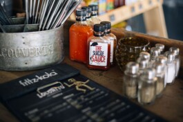 Scharfte Sauce steht auf einem Schrank neben Besteck und Pfeffer und Salz.