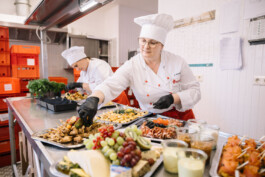 Zwei Mitarbeiterinnen richten mehrere Platten mit Essen an.