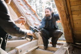Mitarbeiter des Betriebs Specht & Schwalbe reichen sich auf einer Baustelle Werkzeug.