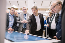 Robert Habeck bedient ein Touch-Screen umringt von Ausstellern des Messestands. 