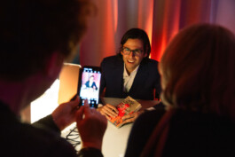 Autor Deniz Utlu lächelt mit seinem Buch in eine Handykamera.