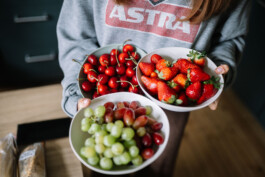 Litti trägt gefüllte Obstschalen mit Kirschen, Erdbeeren und Trauben.