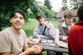 Hannes und Ali sitzen am Picknick-Tisch und unterhalten sich mit Gästen der Marburg WG.