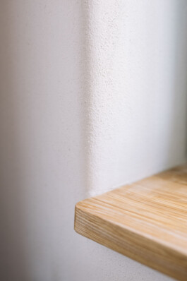 Blick auf eine Lehmwand mit einem Fensterbrett aus Holz